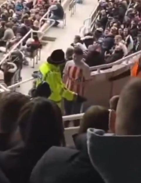 A security guard speaking to a spectator in a stadium.