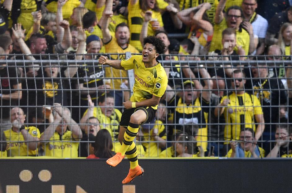 Jadon Sancho celebrates a goal in front of cheering fans.