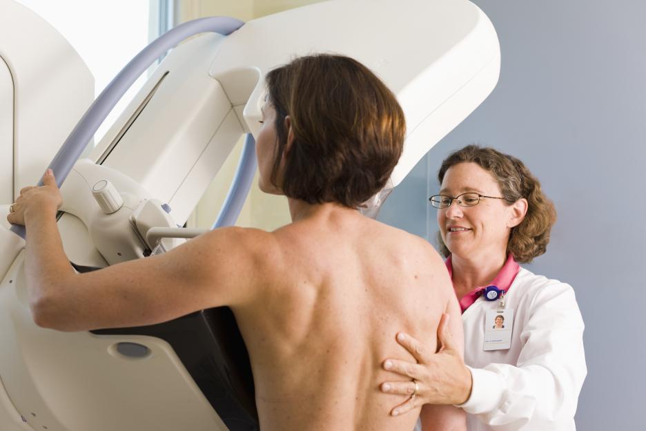 Medical technician assisting patient during mammogram.