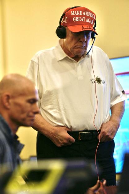 President Donald Trump wearing a "Make America Great Again" hat and headset.