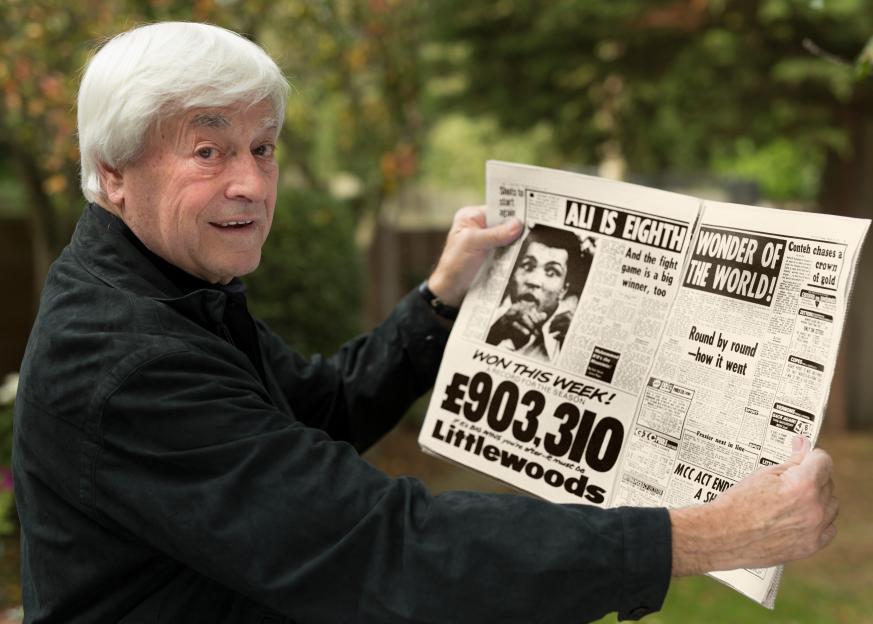 Man holding a newspaper with a headline about Muhammad Ali.