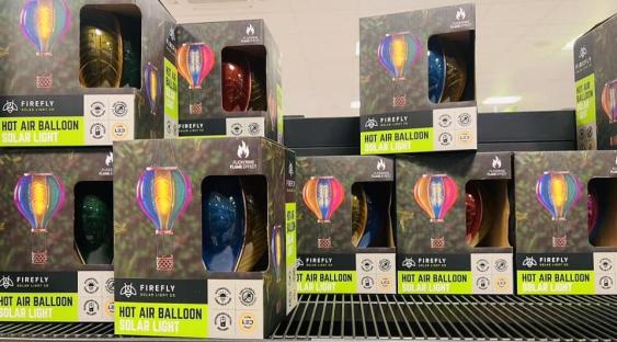 Several boxes of Firefly hot air balloon solar lights on a shelf.