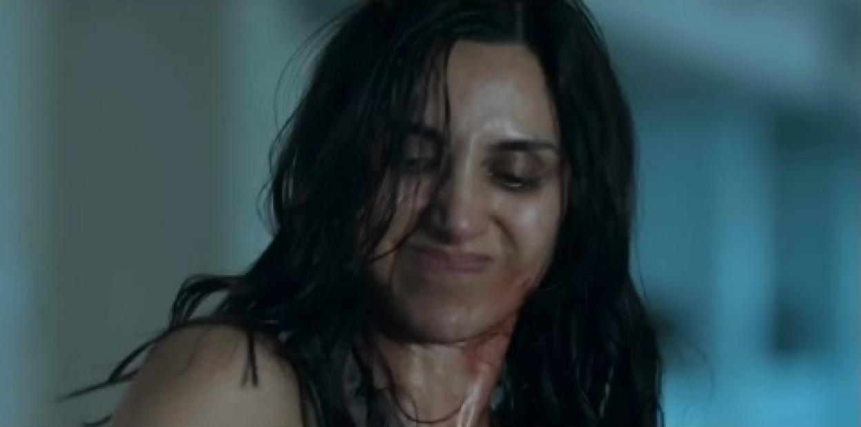 Screenshot of a woman with blood on her neck and face.