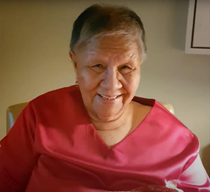 Smiling older woman in a red shirt.