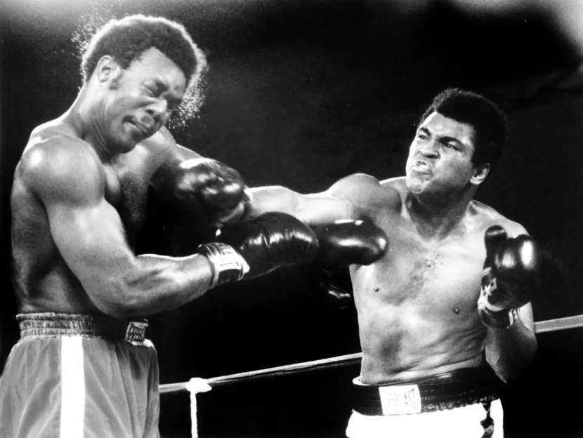 Black and white photo of two boxers in the ring, one throwing a punch.