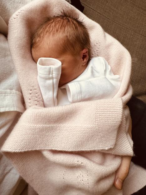 Newborn baby wrapped in a pink blanket.