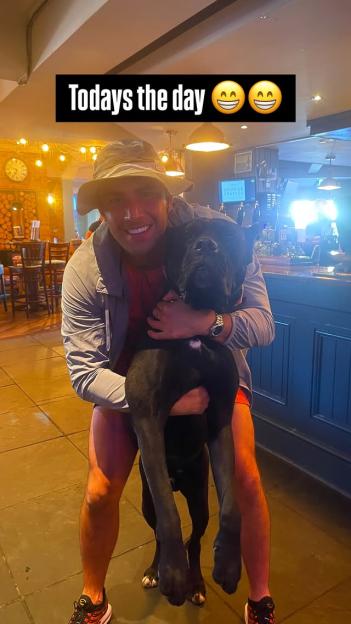 Man holding a large black dog.