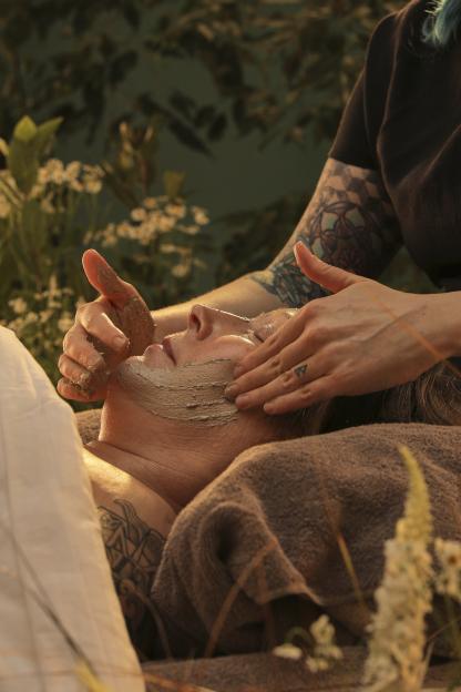 A person receiving a facial treatment with a mud mask.