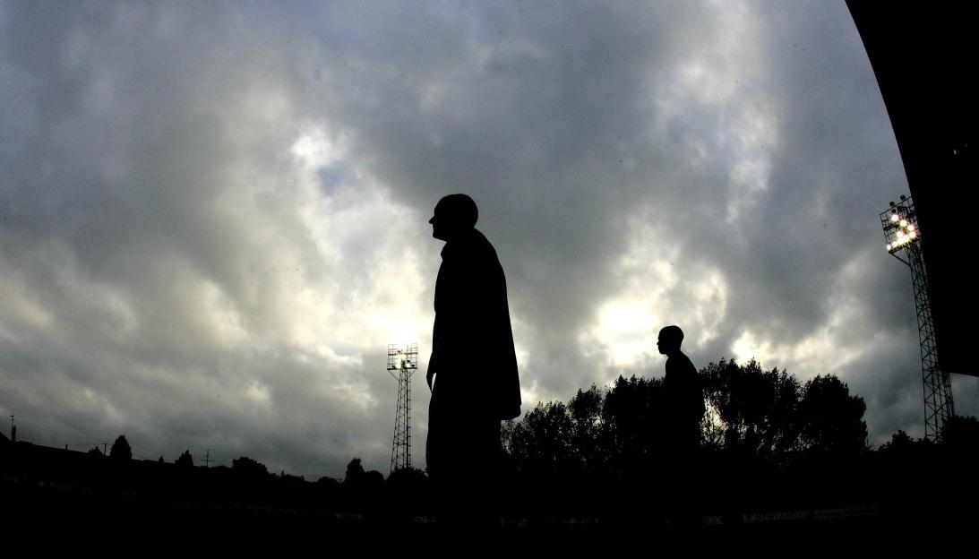 Silhouette of two men at a soccer field.