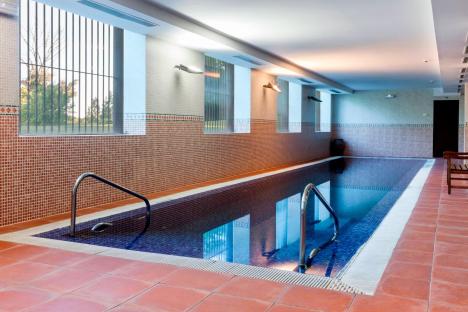 Indoor swimming pool with tiled walls and railings.