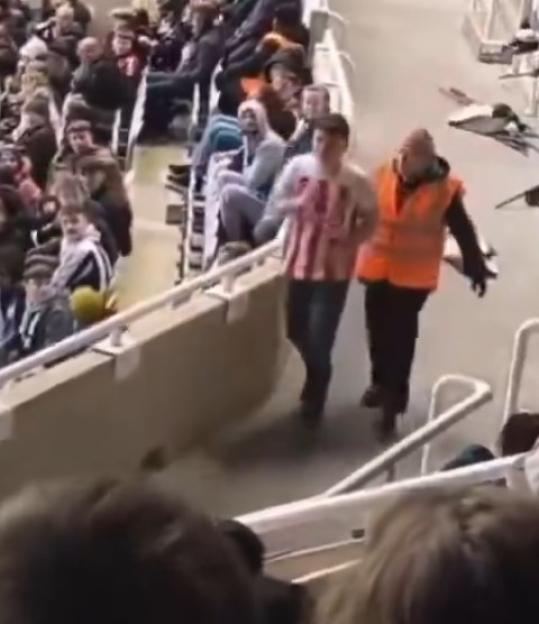 A stadium steward escorting a fan down the stairs.