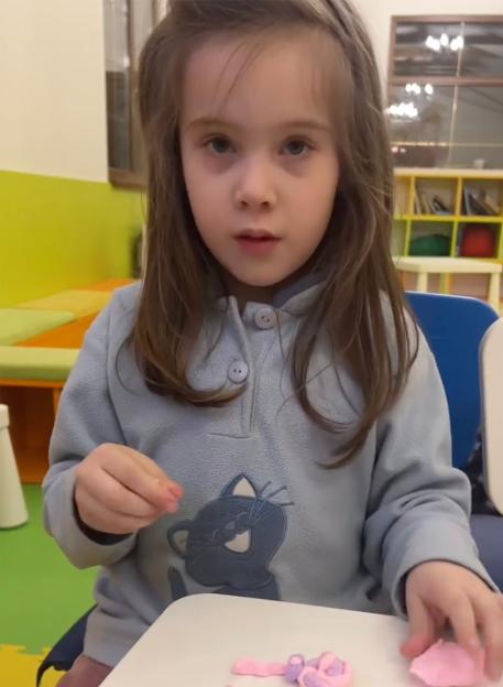 Girl playing with playdough, mourning the death of a friend in a drone attack.