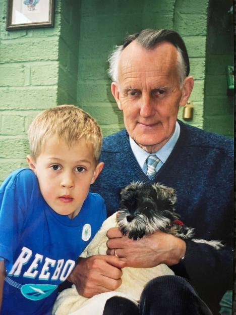 Photo of a grandfather holding a small dog and a young boy.