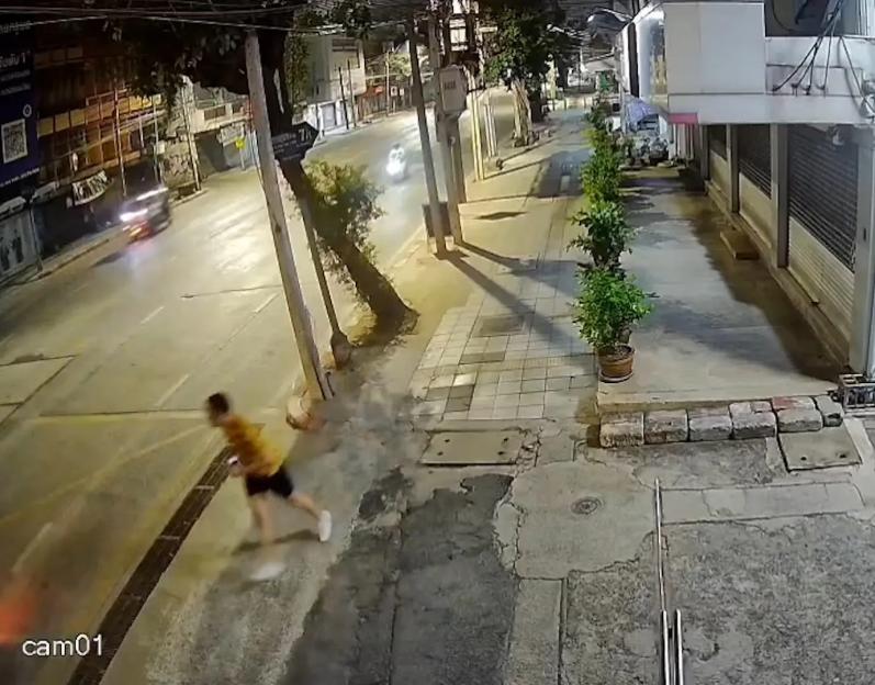 CCTV footage of a man in a yellow shirt running down a street at night.